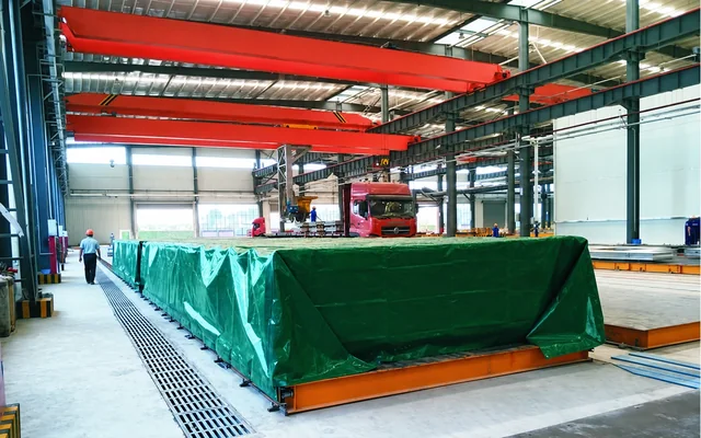 Retractable curing cover positioned over a casting bed in a precast concrete workshop