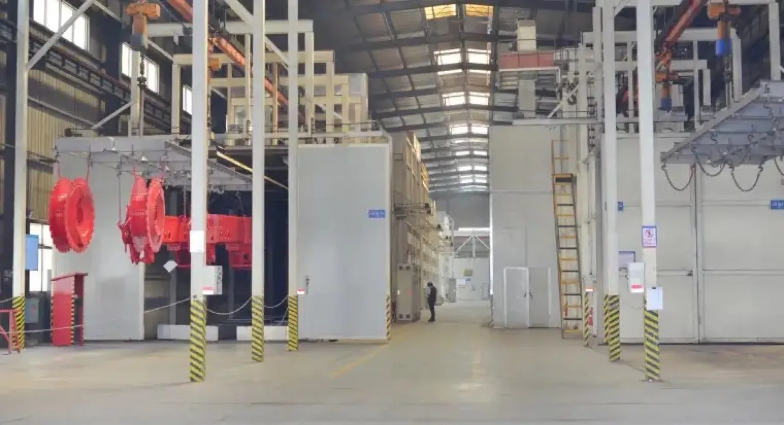 Surface treatment and finishing booth inside a steel fabrication workshop showing painted machinery components before packaging