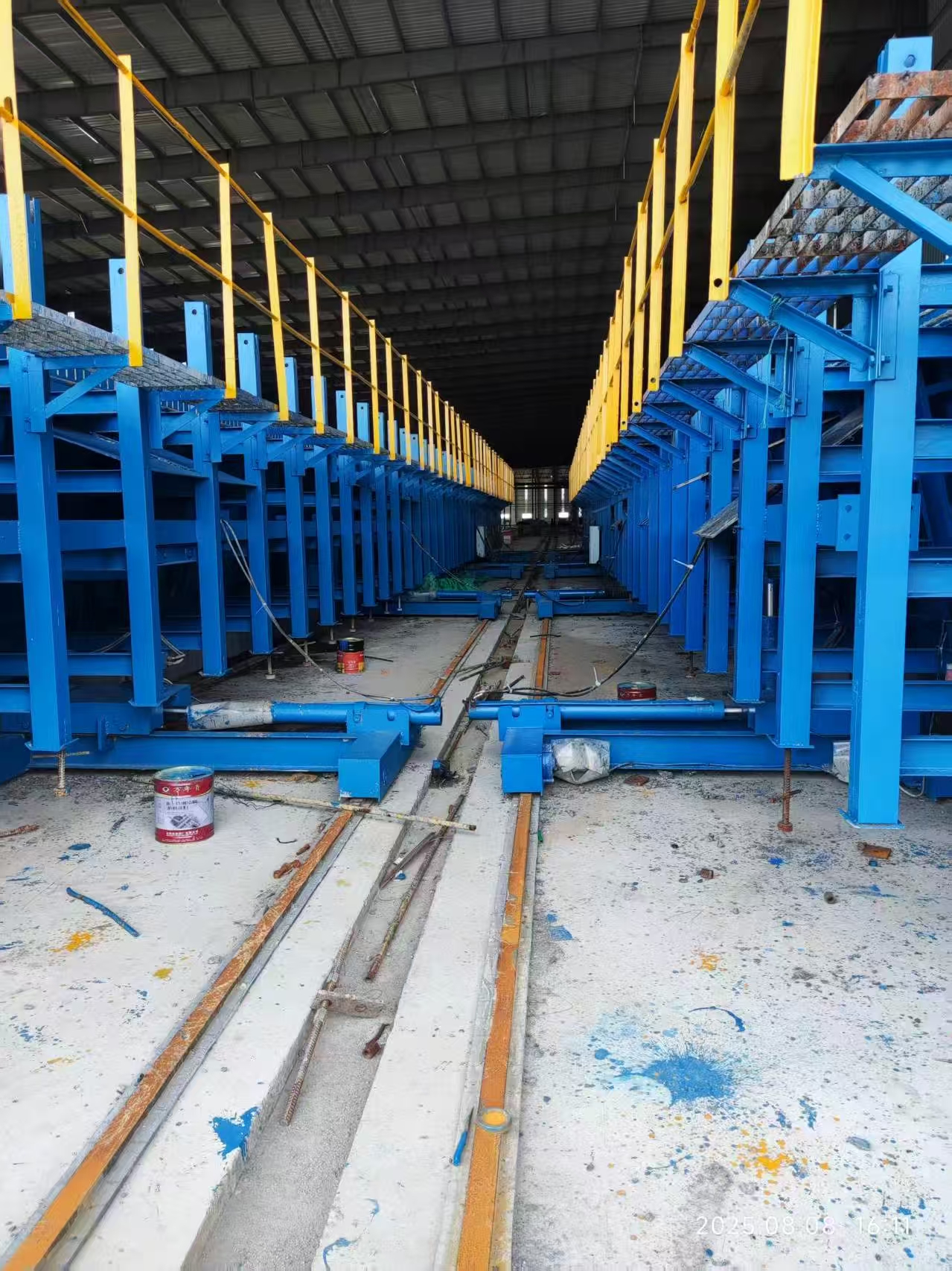 Parallel rows of blue steel U-beam formwork with access platforms and floor rails