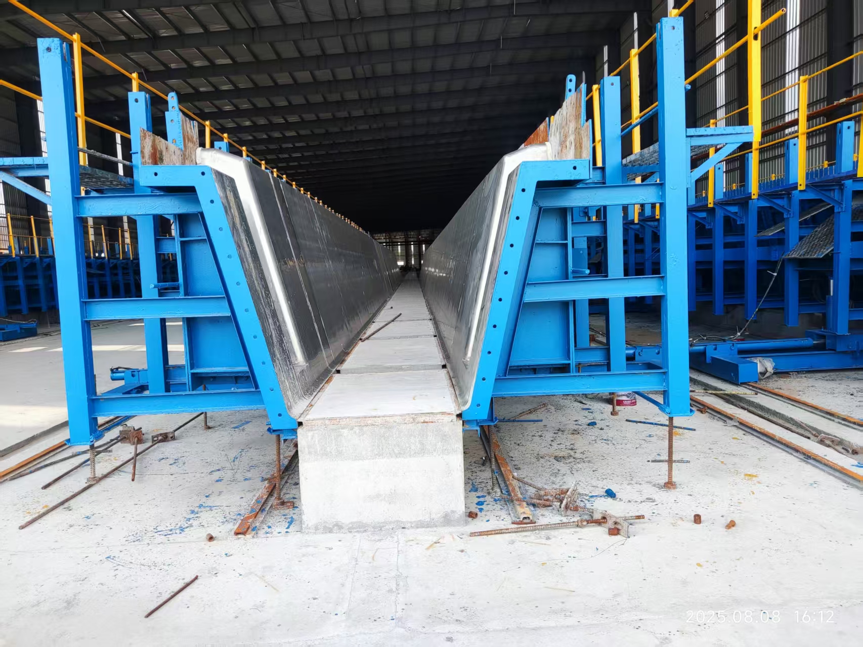 Steel U-beam formwork with inclined mould faces inside a precast bridge component factory