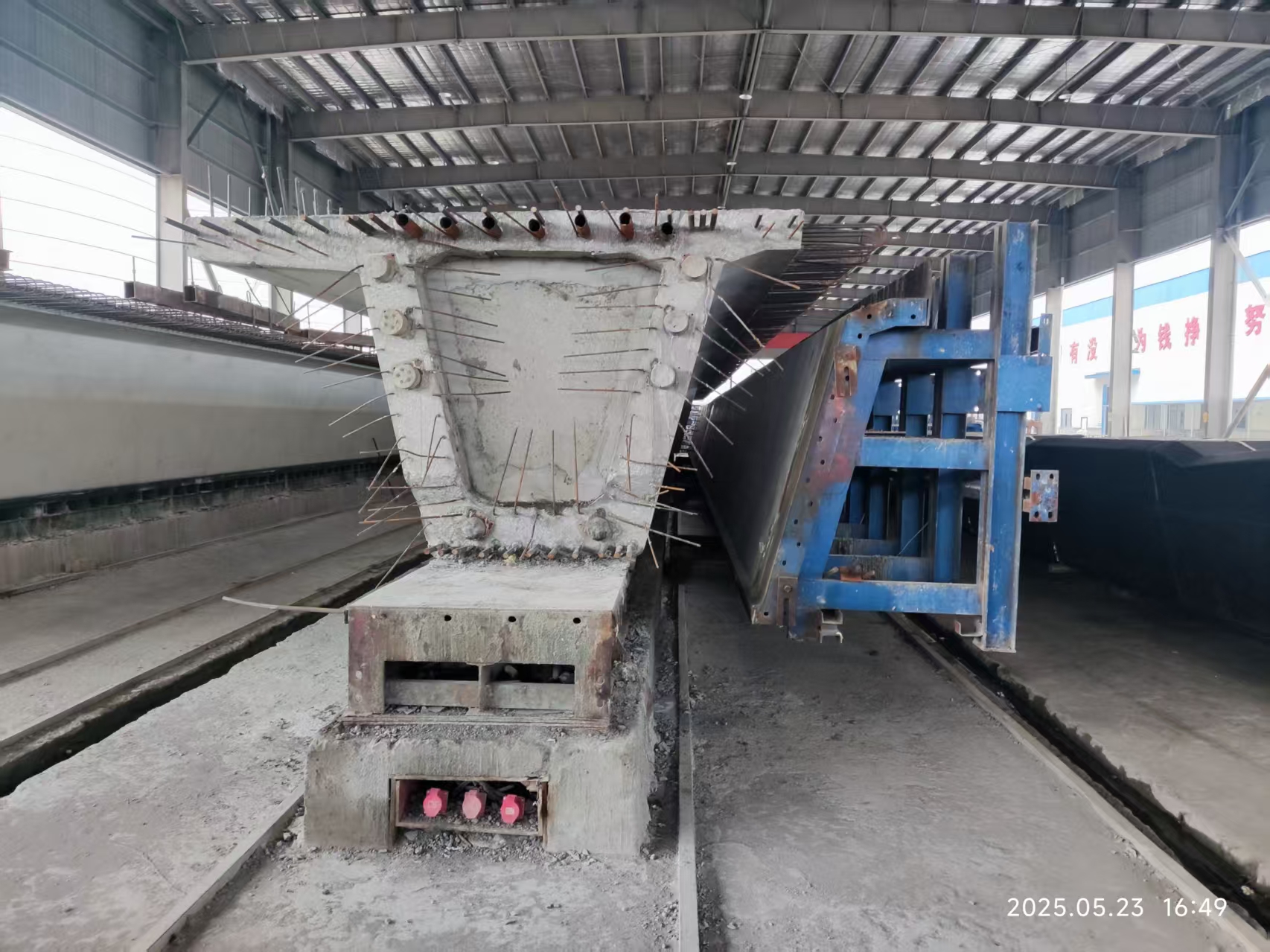 Completed precast U-beam cross-section beside opened steel formwork in a production workshop