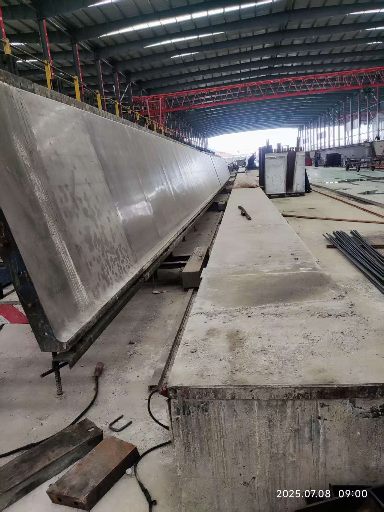 Long inclined steel side form for a precast U-girder inside an industrial production building