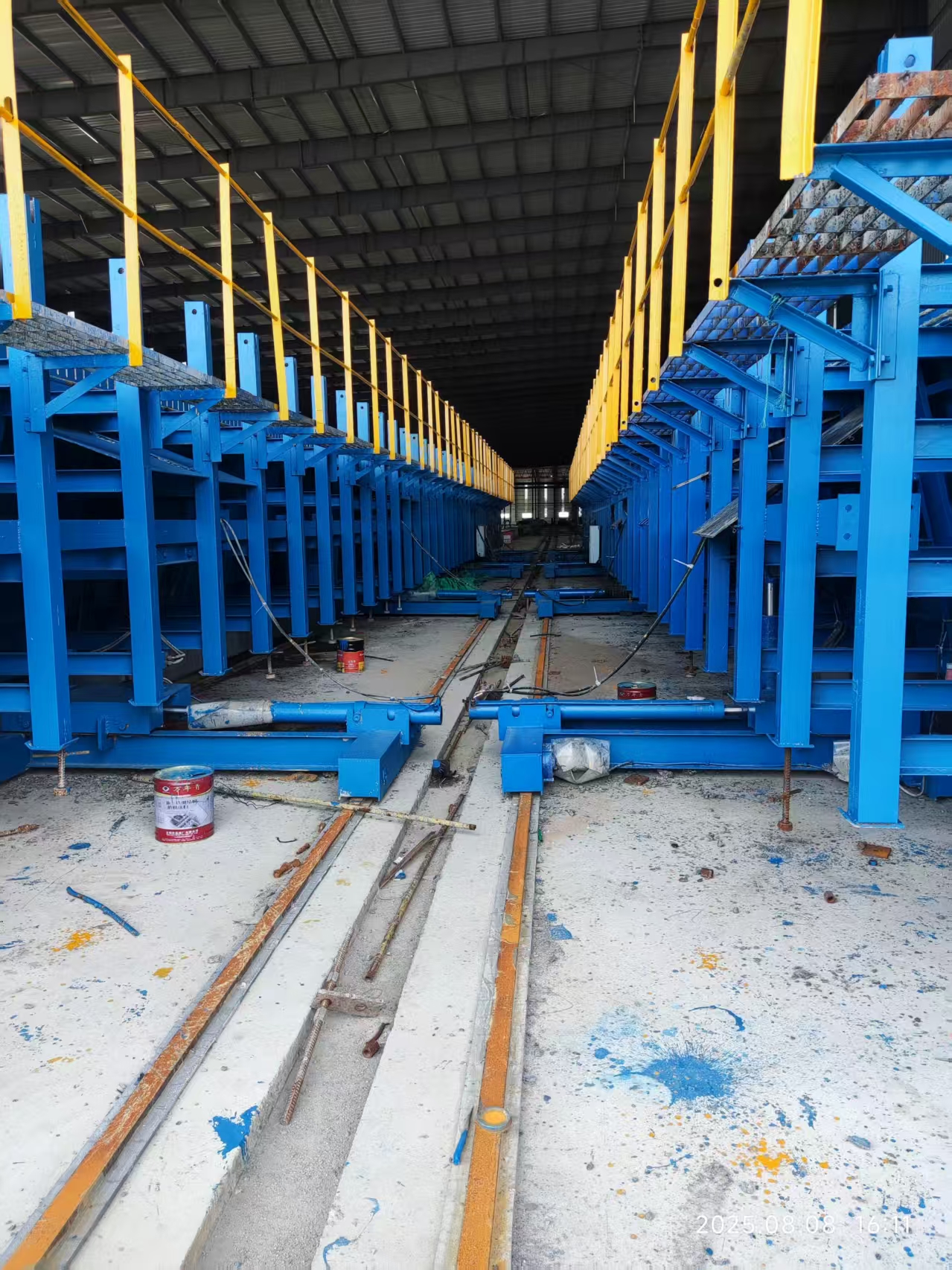 Parallel steel U-girder formwork lines with work platforms and central rail routes in a factory