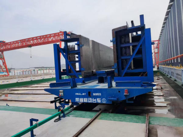 Rail-mounted movable hydraulic formwork carrying a large steel mould in a precast concrete production facility