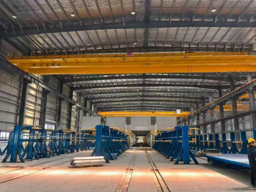Long precast production hall with parallel mould stations, floor rails and overhead cranes